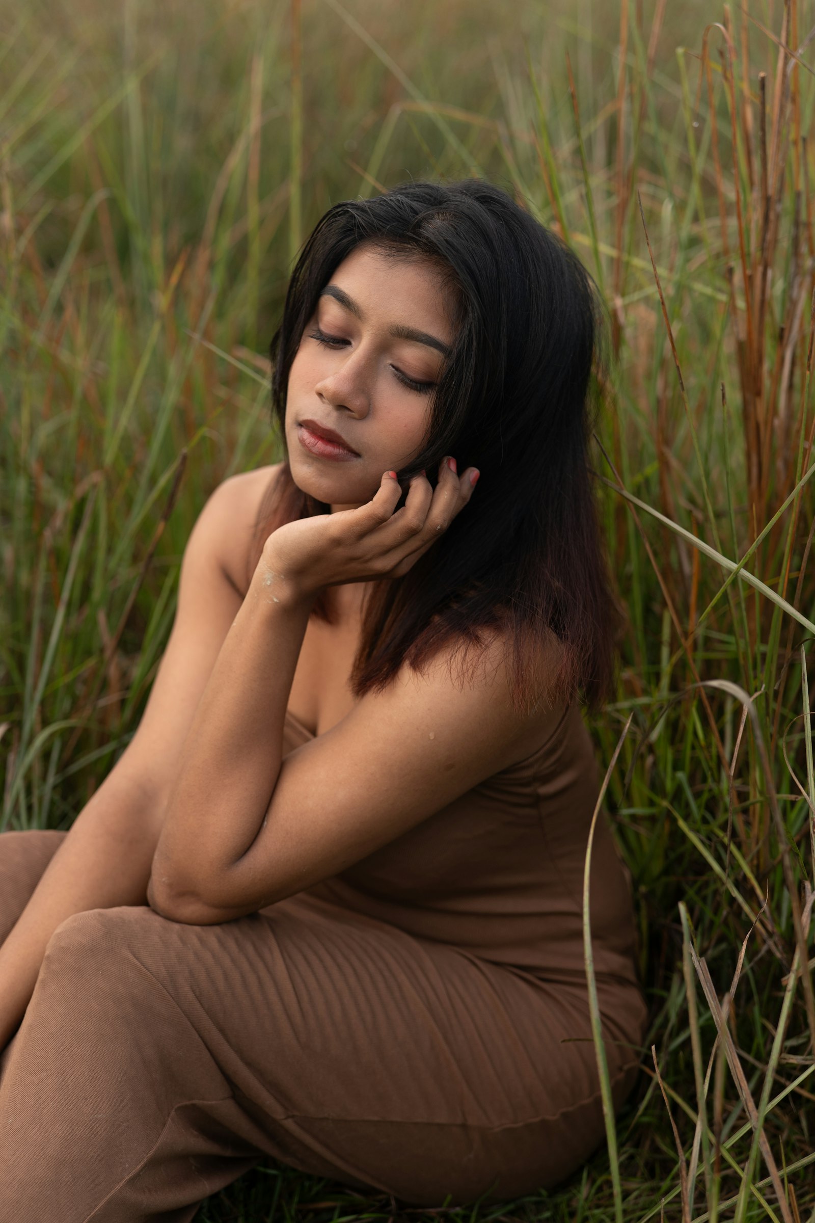 Warm brown dress on tawny skin, sitting in tall grass