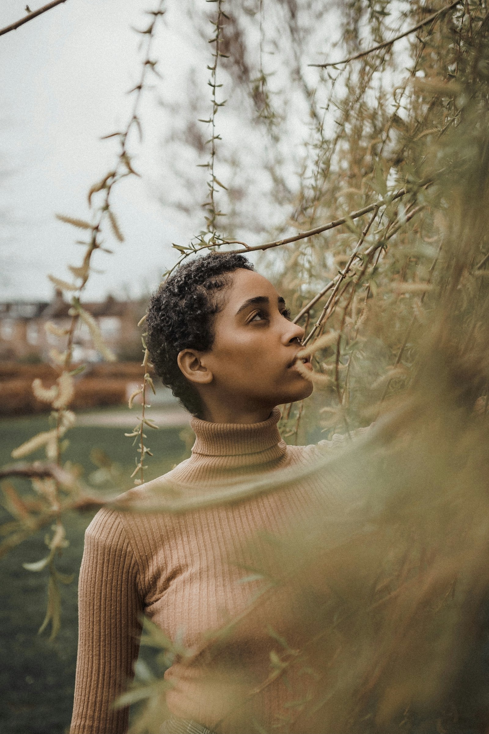 Woman with warm golden-brown skin wearing a camel ribbed turtleneck
